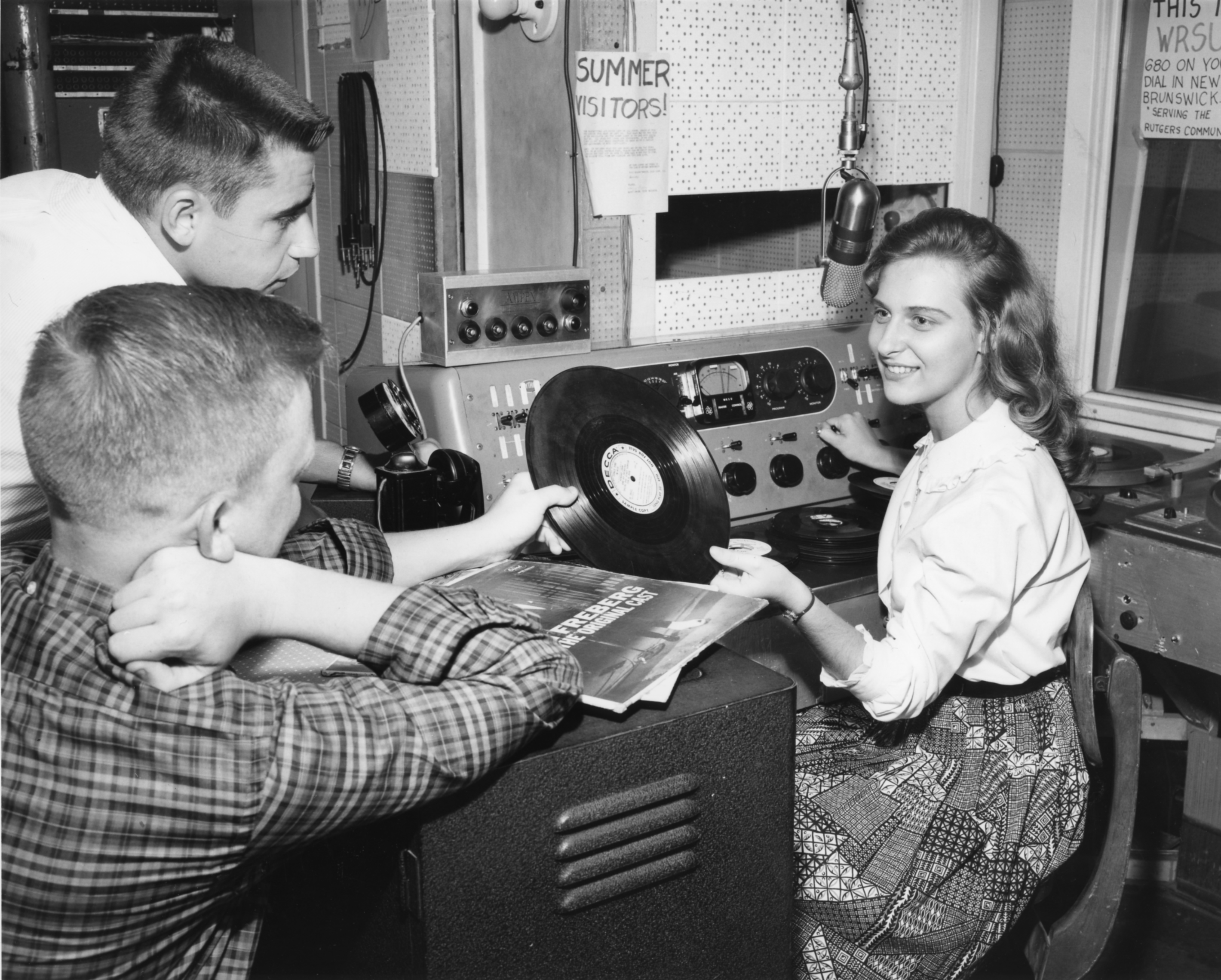 From RUTGERS NEWS SERVICE, year unknown – DOUGLASS DISC JOCKEY: Nineteen year old Ann Sudia of Linden, a sophomore at Douglass College, the women’s division of Rutgers University, spins a request tune over WRSU – the student operated radio outlet in New Brunswick, as two staff members look on approvingly.