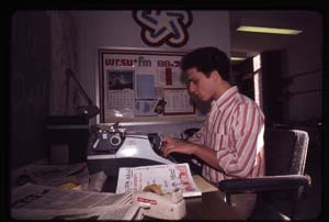 Stuart Brown in the News Room on Typing on a Type Writer for the next News Cast<br/>Notice the Bi-Cencential Logo on the wall.